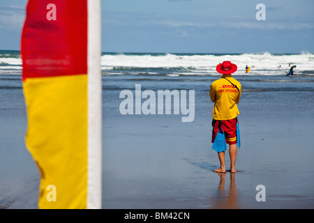 A surf lifesaver watches over swimmers at the beach. Piha, Waitakere Ranges Regional Park, Auckland, North Island, New Zealand Stock Photo
