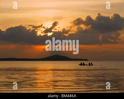 Small fishing motorboat glides in front of Koh Phangan island at sunset, Thailand. View from Mae Nam beach, Koh Samui island. Stock Photo