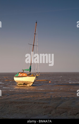 Yacht illuminated by early light at low tide Leigh on Sea Essex England Stock Photo