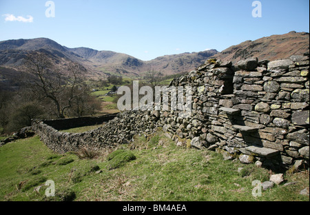 A stile in a dry stone wall looking towards Great Langdale Fells near to Elterwater in the Lake District National Park, Cumbria, Stock Photo