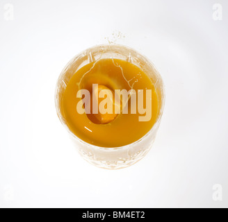 slice of orange splashing into a glass of orange juice from above Stock Photo