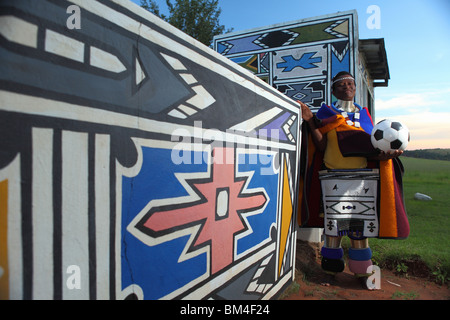 A woman with traditional Ndebele tribe colours stand with a soccer ball in a cultural village in Mpumalanga, South Africa Stock Photo