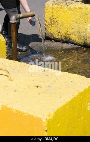 Water bottle is being filled at the free-flowing artesian well in downtown Olympia, Washington. Stock Photo