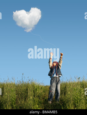 child who catches heart shaped cloud Stock Photo