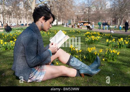 Young woman reading a book in St James's Park, London, England, UK Stock Photo