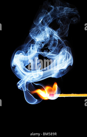 one match is igniting in front of black background with blue smoke Stock Photo
