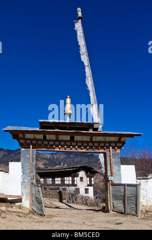 Monastery entrance gate framing village house, Ura, Bumthang, Bhutan Stock Photo