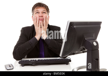 Businessman sitting behind desk is in despair, looking in the sky, over white background Stock Photo