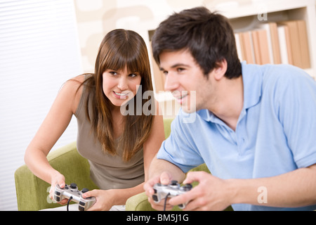 Student - happy teenagers playing video game with control pad in living room Stock Photo