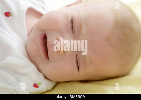 baby crying sad laying on the yellow bed Stock Photo