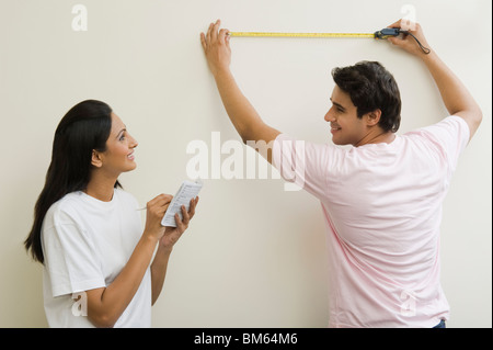 Couple measuring the wall with a tape measure Stock Photo
