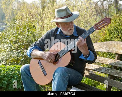 OLDER MAN PLAYING CLASSICAL GUITAR OUTDOORS Stock Photo