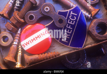 Close up of old metal bits and pieces such as screws and nuts with two badges among them stating Swimming and Prefect Stock Photo