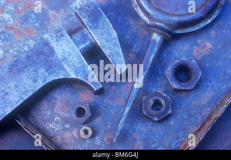 Small adjustable spanner or wrench lying with flat oilcan and metal nuts in shallow tin tray Stock Photo