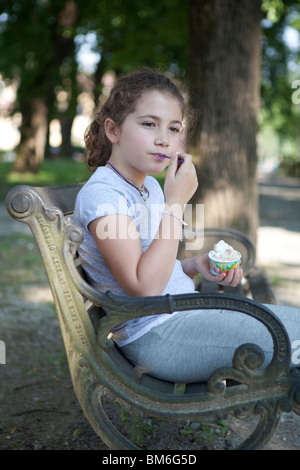 Child having an ice cream at the park sitting on a bench Stock Photo