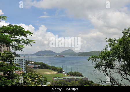University of Hong Kong Stanley Ho Sports Centre and container ships in east Lamma channel, viewed from Victoria Road, Hong Kong Stock Photo