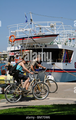Cyclists on the quay in Kos Town Greece by a ferryboat which ferries passengers to Bodrum Turkey Stock Photo