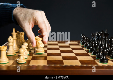 Hand moving a knight chess piece on wooden chessboard Stock Photo