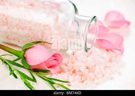 Pink bath salts in a glass jar with flowers and herbs Stock Photo