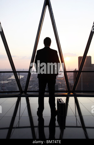 A businessman stand with his briefcase at the top of the Gherkin skyscraper in the city of London, U.K. Stock Photo