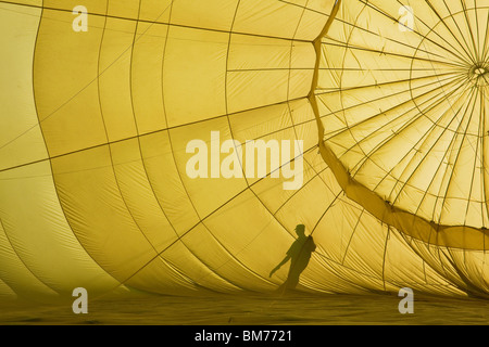 A man is silhouetted against a partially inflated hot air balloon before its flight Stock Photo