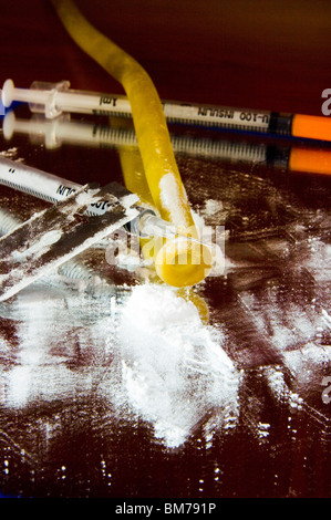 Close-up of cocaine and a syringe of insulin, a tourniquet and a razor blade with the background a siringe. Stock Photo