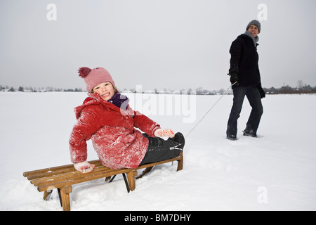 A man pulling a sled daughter on it Stock Photo
