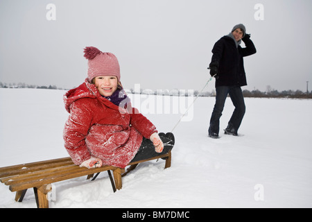 A man pulling a sled daughter on it Stock Photo