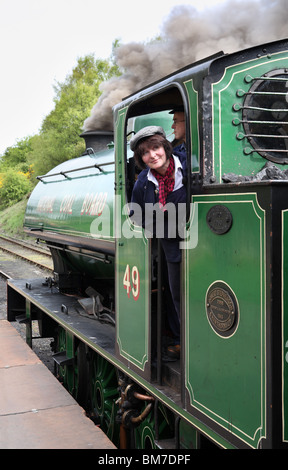 The lady 'fireman' of Tanfield Railway No. 49 looks out for the guard's signal at Andrews House station, Gateshead, England Stock Photo