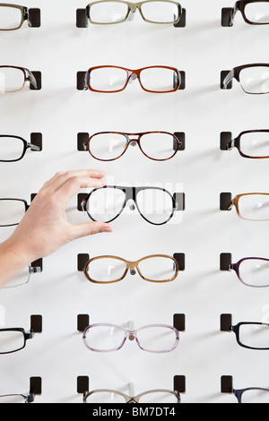 A human hand choosing a pair of glasses in an eyewear store Stock Photo