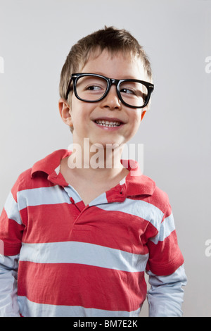 A young boy wearing fake glasses and smiling slyly, studio shot Stock Photo