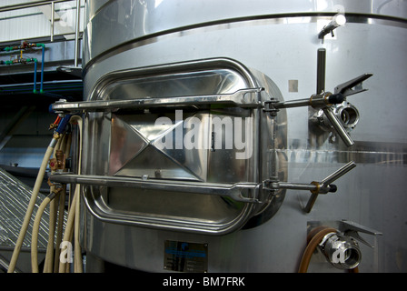 Heavy duty hatch door at bottom of stainless steel fermentation tanks in Tantalus Winery cellar Stock Photo