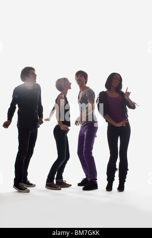 Four young people dancing, studio shot, white background, back lit Stock Photo