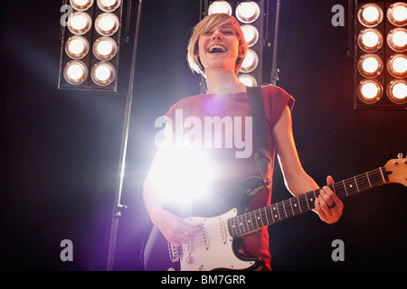 A woman playing electric guitar performing on stage Stock Photo