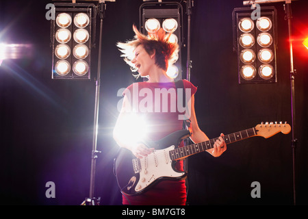 A woman playing electric guitar performing on stage Stock Photo