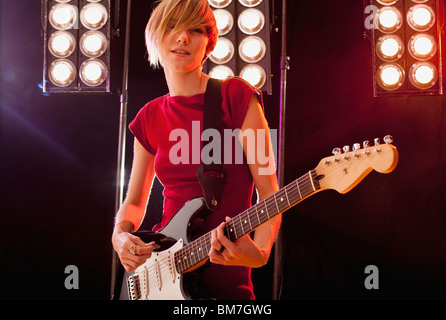 A woman playing electric guitar performing on stage Stock Photo