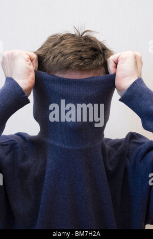 man pulling up collar of pullover Stock Photo