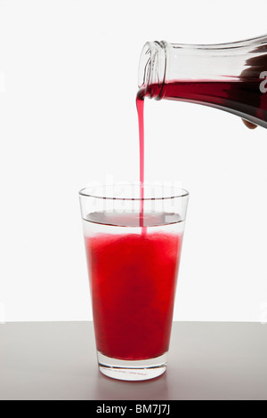 Detail of fruit syrup being poured into a glass of water Stock Photo