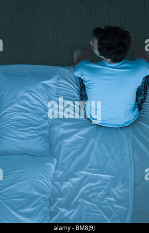 Man sitting on bed unable to sleep Stock Photo - Alamy