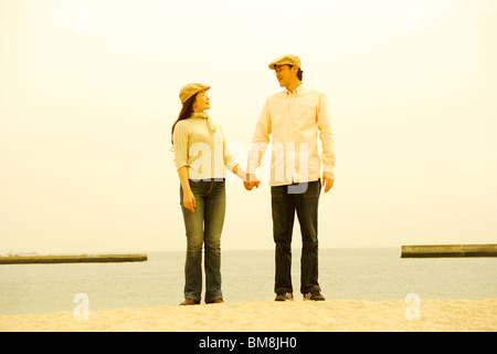 Mature couple in flat cap standing by sea, hand in hand Stock Photo