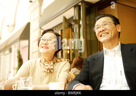 Senior couple sitting at table in cafe, smiling Stock Photo