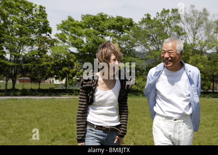 Senior man and mature woman walking in park, smiling Stock Photo