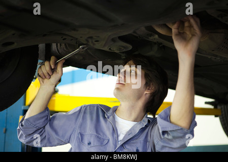 Mechanic working on underside of car elevated on hydraulic lift Stock Photo