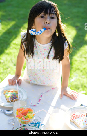 Girl at party enthusiastically blowing party horn blower Stock Photo ...