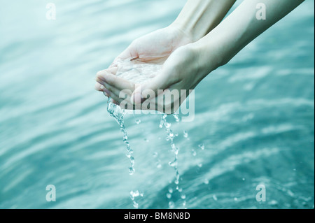 Woman scooping up water with hands Stock Photo