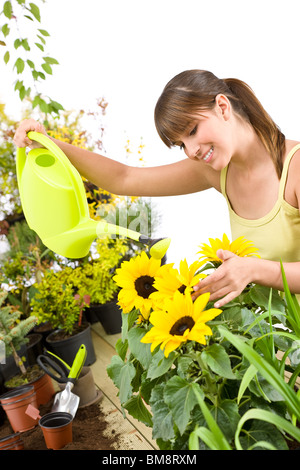 Gardening - woman with watering can and flowers pouring water on white background Stock Photo