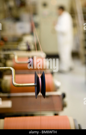 Recyclable composite textile fabrication department of factory, machinist working on thread coating machine Stock Photo