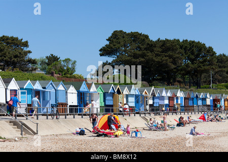 Row of colourful beach huts and holiday makers on the seafront of Mudeford. Stock Photo