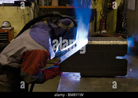 Coated textile plant, maintenance workshop, welder performing arc welding Stock Photo