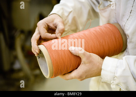 Recyclable composite textile fabrication department of factory, worker performing quality control on thread Stock Photo